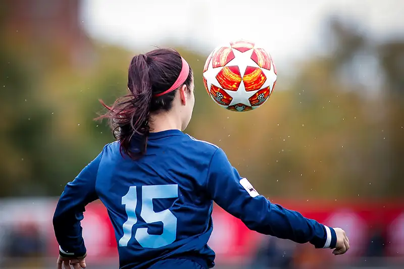 Woman facing away kicking a football